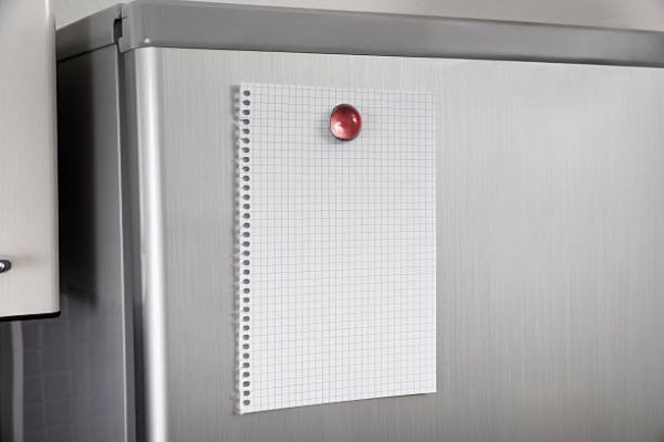 Close-up Of Blank Paper Posted On Modern Refrigerator Door